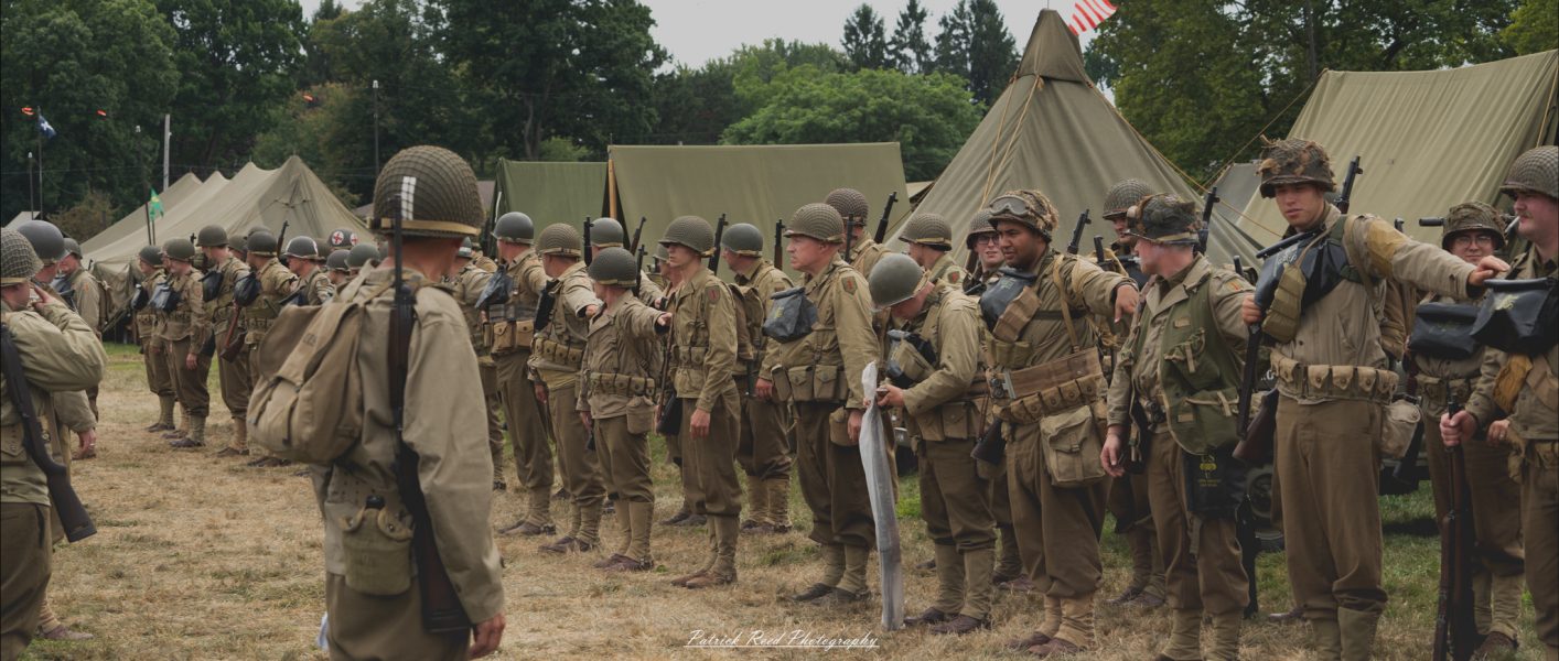 Soldiers standing in precise formation on a parade field, their uniforms immaculate and posture rigid. The scene reflects discipline and unity, as rows of soldiers present a powerful display of military order and readiness.